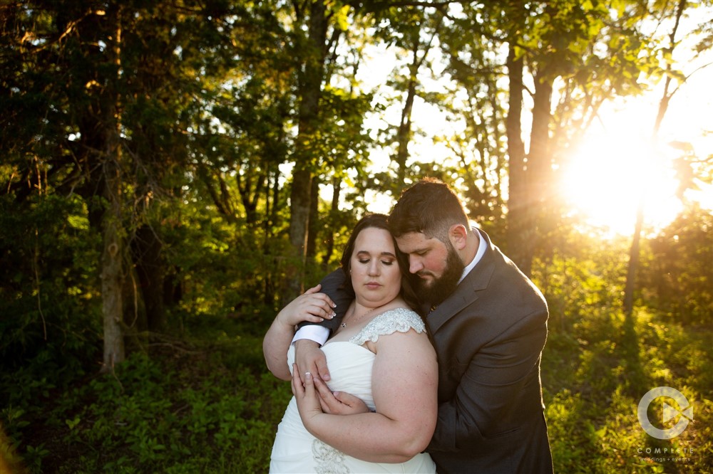 groom hugs bride in the woods