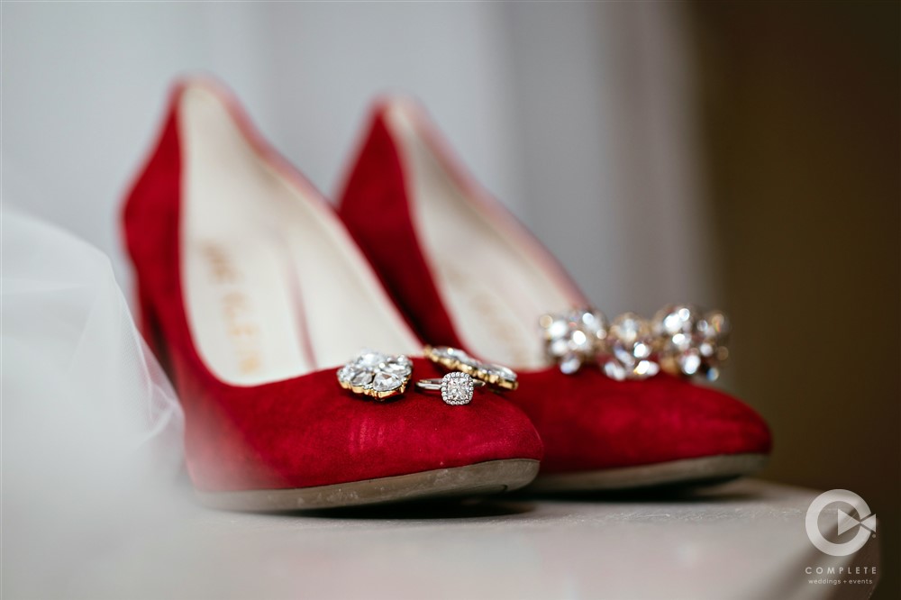 focus shot of wedding ring on bride's red shoes