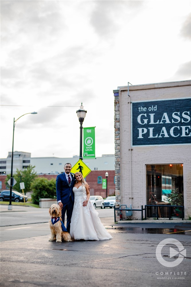 bride groom and dog in front of old glass place