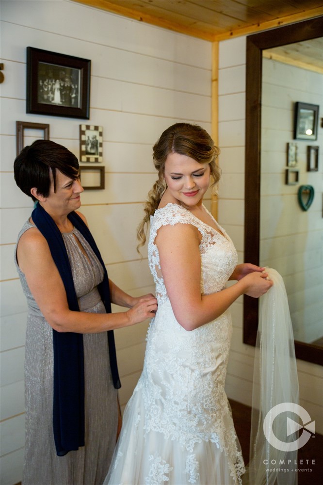 bride being buttoned up before ceremony