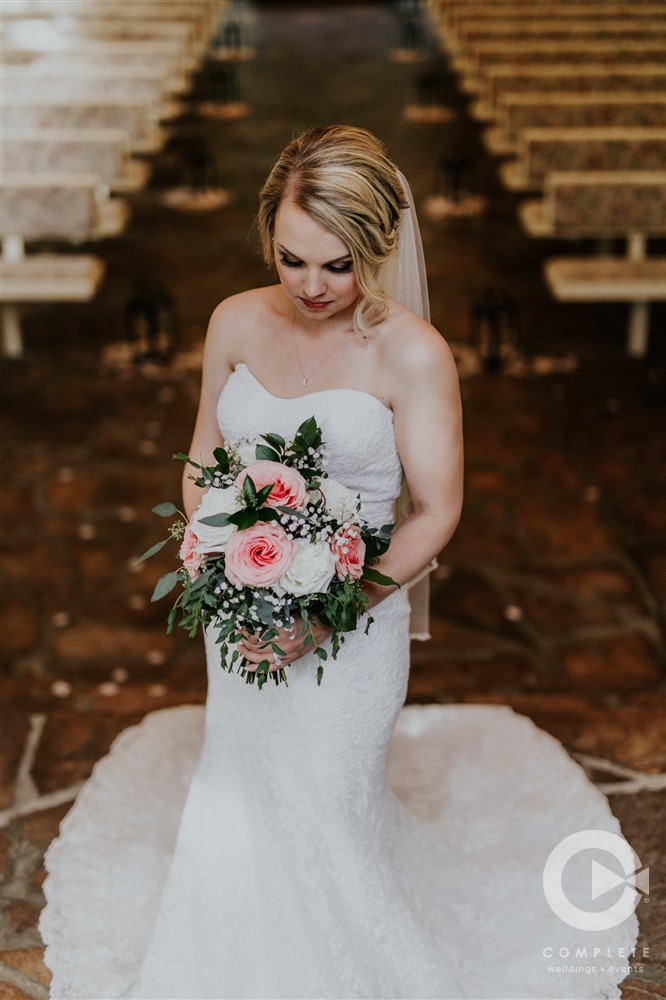bride looking at her pink and white bouquet