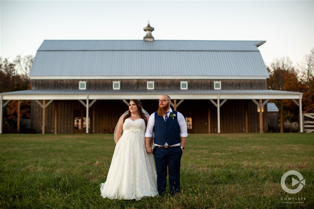 Couple posed outside rustic barn