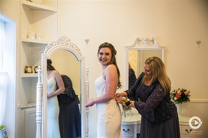 Bride laughing as putting on her wedding dress