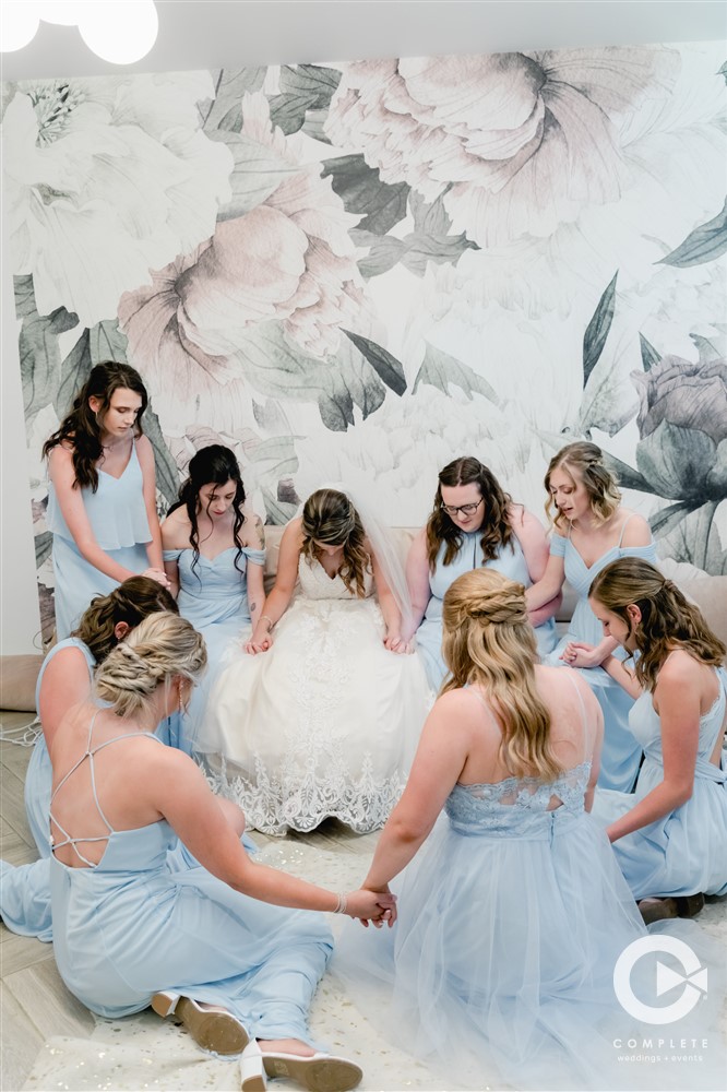 Bride praying with bridesmaids