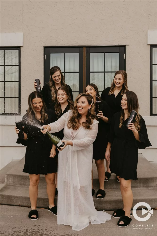 Complete Weddings + Events Photography, Wedding party Photos, bride with her bridesmaids, bride popping a bottle of champagne