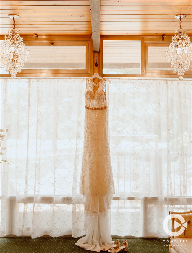 Complete Weddings + Events Photography, Wedding Gown hanging in front of windows